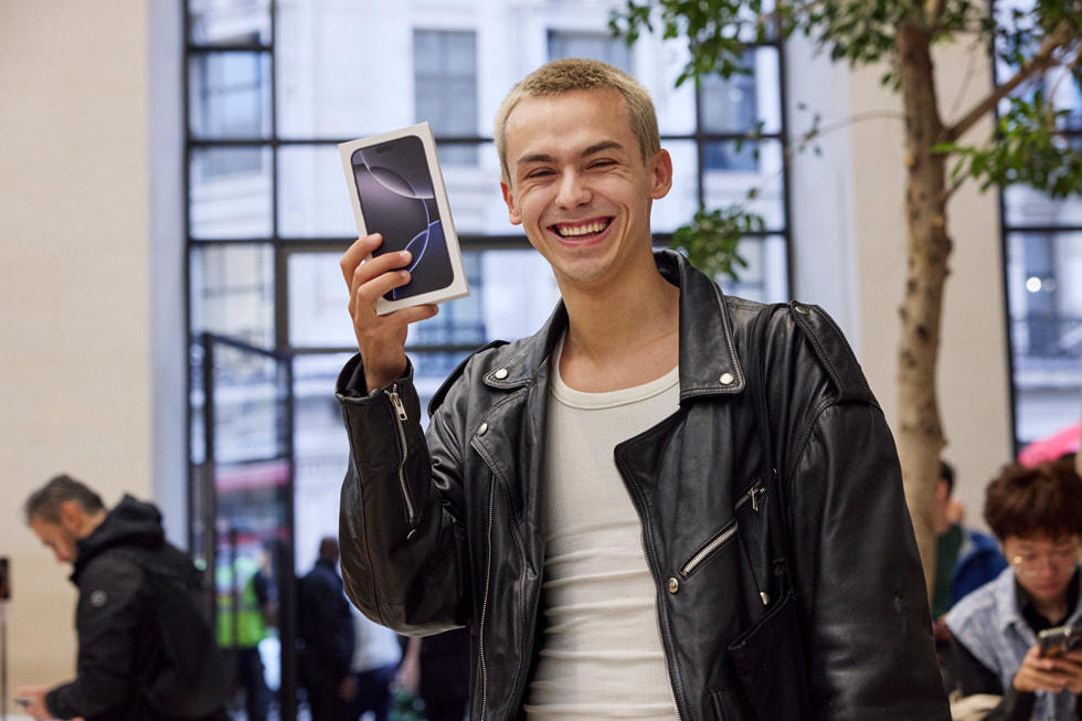 Happy customer holding a new iPhone box after selling their old iPhone for cash near Raleigh, NC