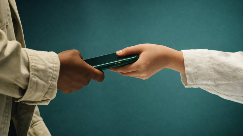 Person handing a green smartphone to another person